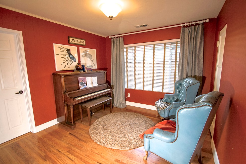 Réalisation d'une salle de séjour tradition avec une salle de musique, un mur rouge et un sol en bois brun.