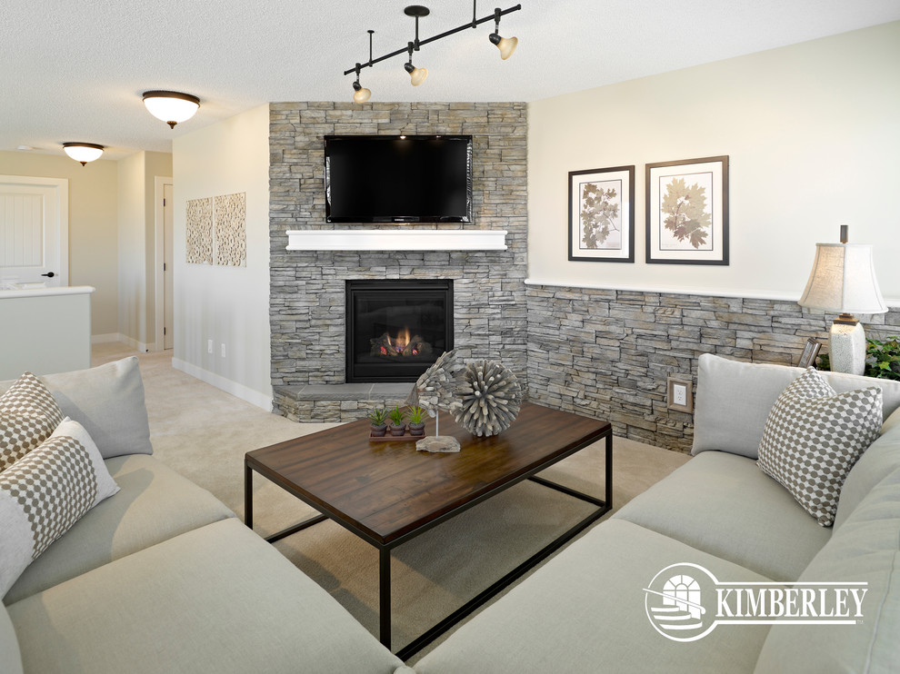 Ejemplo de sala de estar tipo loft tradicional con paredes beige, moqueta, todas las chimeneas, marco de chimenea de piedra y televisor colgado en la pared