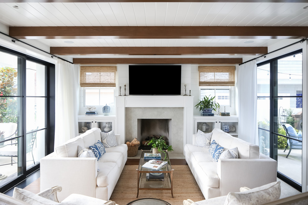Inspiration for a nautical games room in Orange County with white walls, dark hardwood flooring, a standard fireplace, a concrete fireplace surround and a wall mounted tv.
