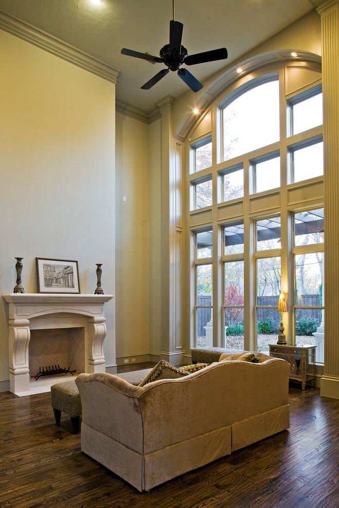 Großes Mediterranes Wohnzimmer im Loft-Stil mit beiger Wandfarbe, dunklem Holzboden, Kamin, Kaminumrandung aus Stein, TV-Wand und braunem Boden in Dallas