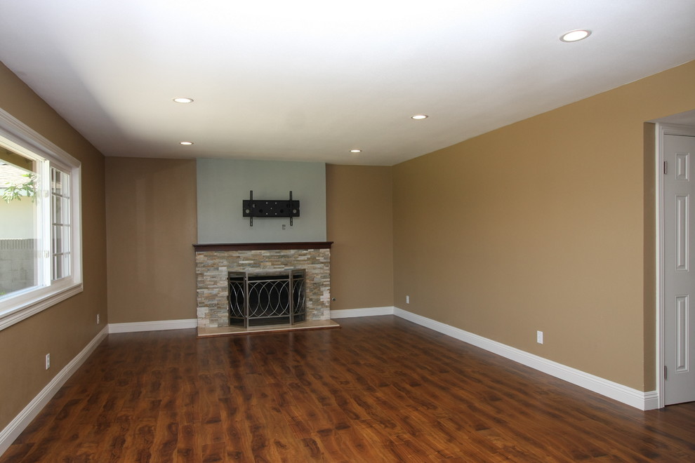 This is an example of a medium sized contemporary open plan games room in Orange County with beige walls, medium hardwood flooring, a standard fireplace, a stone fireplace surround and a wall mounted tv.
