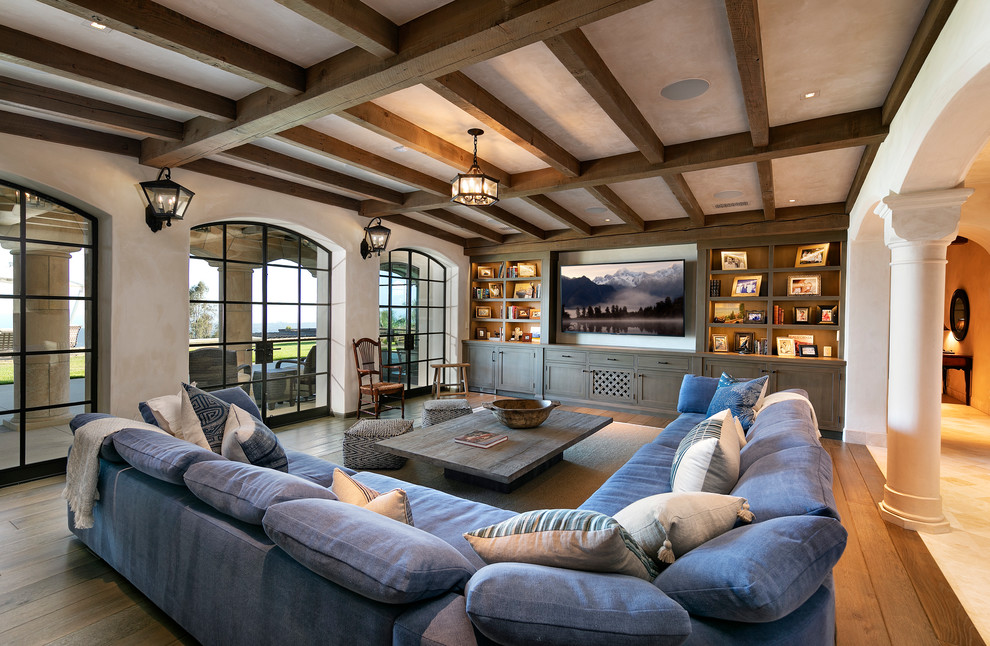 Design ideas for a large mediterranean open plan games room in Santa Barbara with a reading nook, beige walls, no fireplace, a wall mounted tv and brown floors.