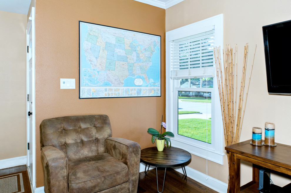 Ejemplo de sala de estar abierta de estilo americano pequeña sin chimenea con paredes beige, suelo de madera oscura, televisor colgado en la pared y suelo marrón