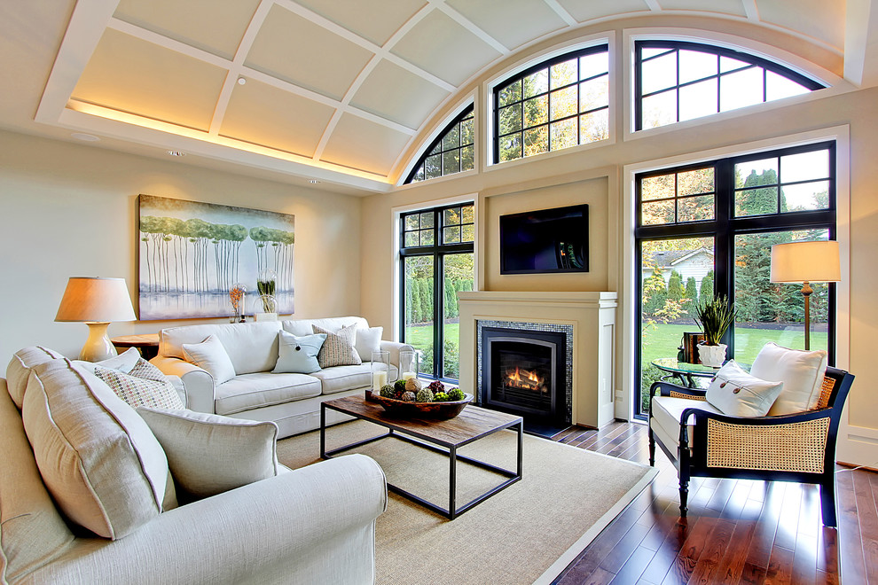 Trendy medium tone wood floor family room photo in Seattle with beige walls, a standard fireplace, a tile fireplace and a wall-mounted tv