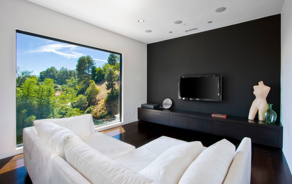Inspiration for a contemporary open concept dark wood floor and brown floor family room remodel in Los Angeles with black walls and a wall-mounted tv