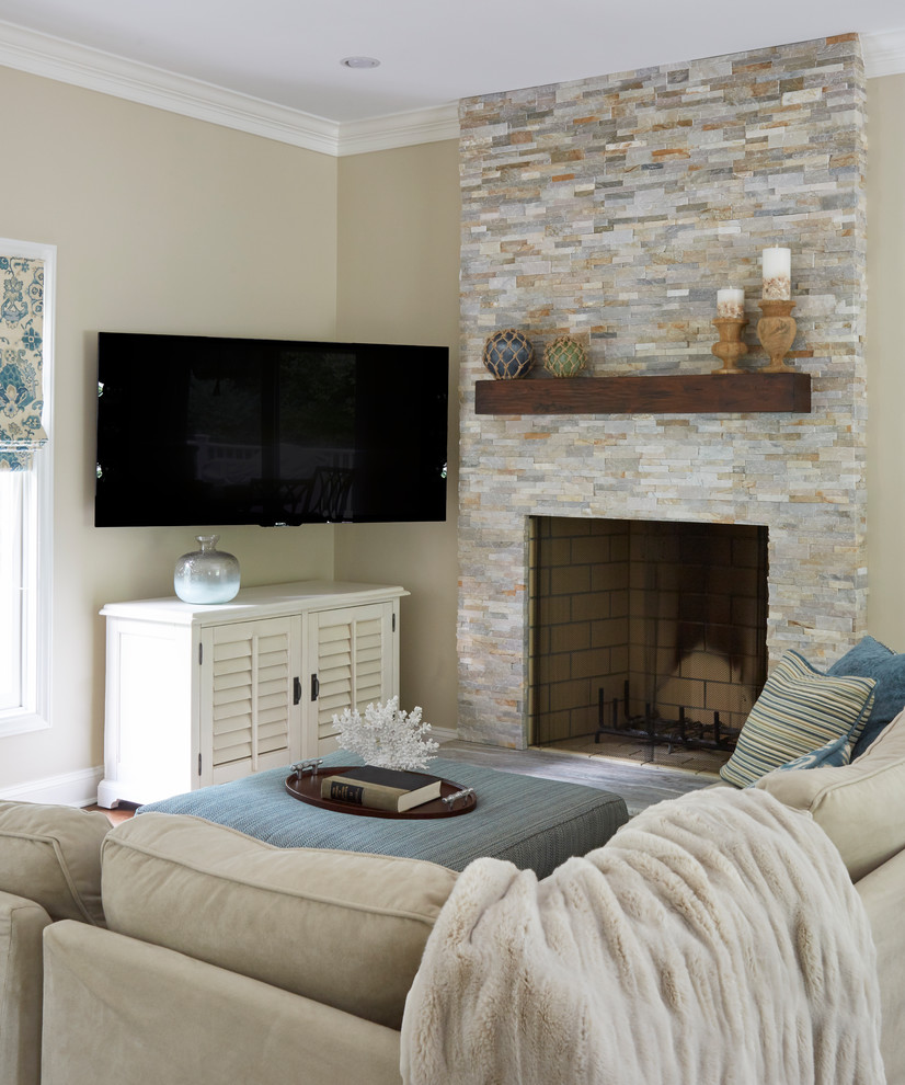 Cette photo montre une petite salle de séjour chic ouverte avec un mur beige, un sol en bois brun, une cheminée standard, un manteau de cheminée en pierre, un téléviseur fixé au mur et un sol marron.