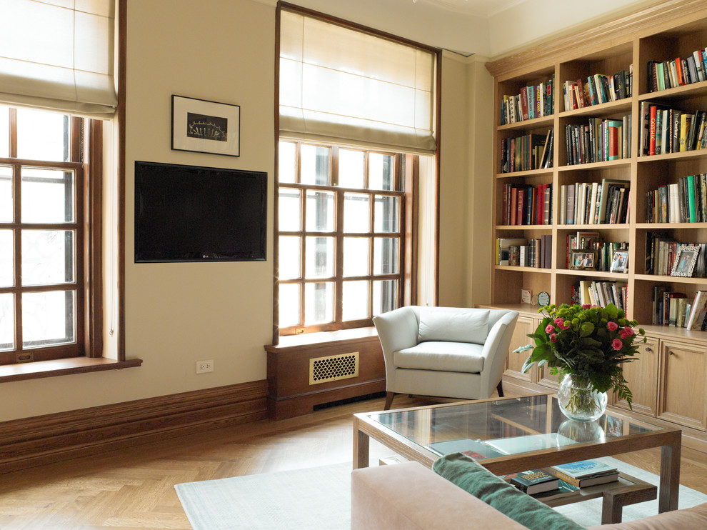 Cette photo montre une salle de séjour chic de taille moyenne et ouverte avec une bibliothèque ou un coin lecture, un mur beige, un sol en bois brun, aucune cheminée et un téléviseur fixé au mur.