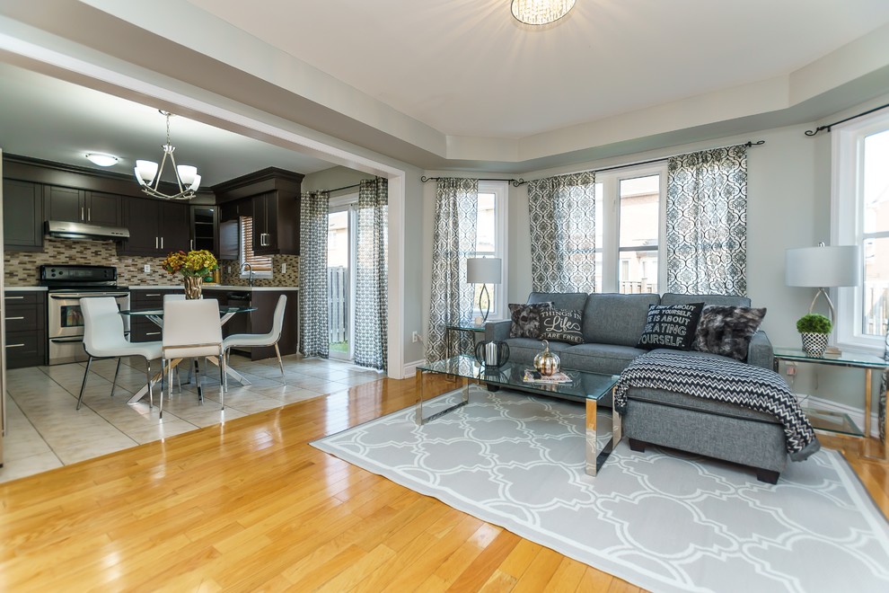 Imagen de sala de estar abierta contemporánea de tamaño medio con paredes grises, suelo de madera clara, televisor independiente y suelo amarillo