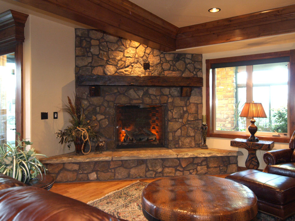 Imagen de sala de estar abierta tradicional con paredes beige, suelo de madera clara, chimenea de esquina y marco de chimenea de piedra