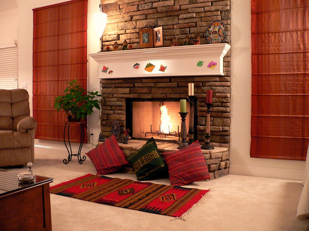 Пример оригинального дизайна: гостиная комната в стиле фьюжн с бежевыми стенами, ковровым покрытием, стандартным камином и фасадом камина из кирпича