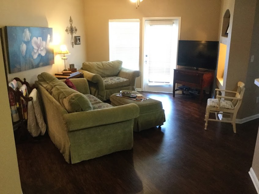 Ejemplo de sala de estar abierta pequeña con paredes amarillas, suelo de madera oscura y televisor en una esquina