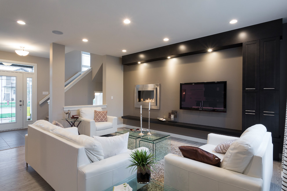 Ejemplo de sala de estar abierta contemporánea pequeña con paredes grises, suelo vinílico, chimenea lineal, marco de chimenea de metal y televisor colgado en la pared