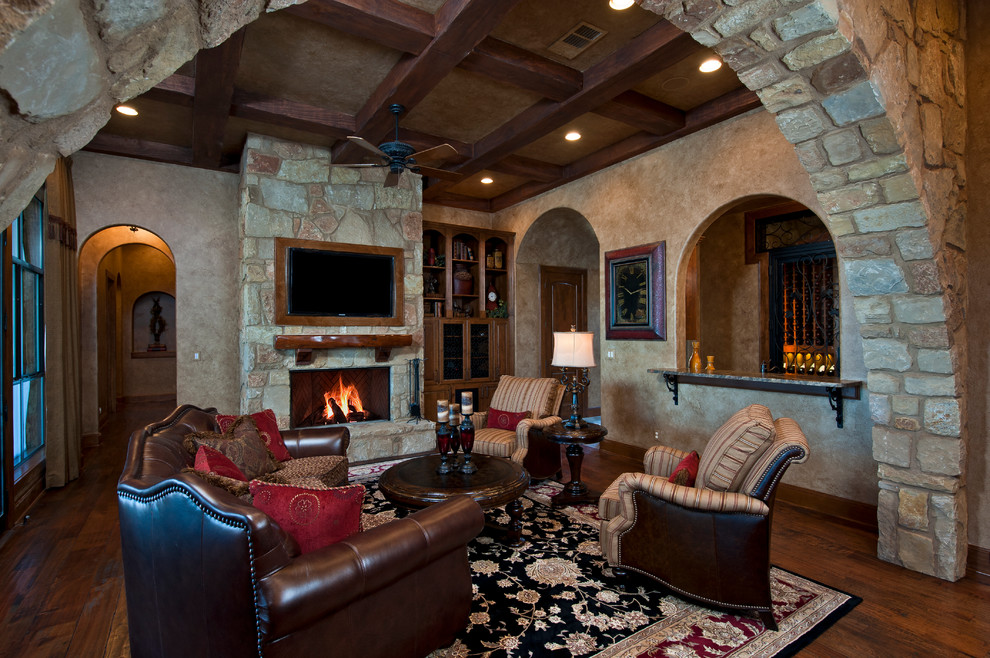 Inspiration for an expansive mediterranean open plan games room in Austin with beige walls, medium hardwood flooring, a standard fireplace, a stone fireplace surround and a built-in media unit.