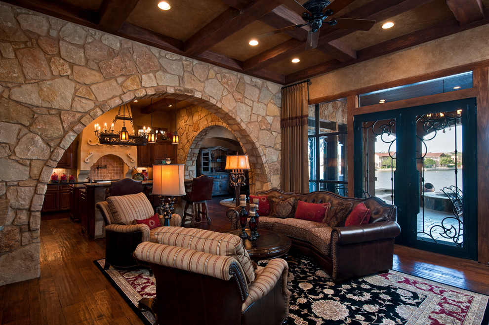 Family room - huge mediterranean open concept medium tone wood floor family room idea in Austin with beige walls, a standard fireplace, a stone fireplace and a media wall