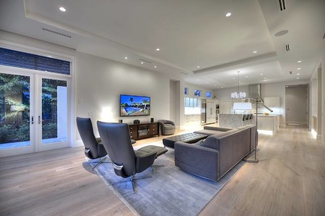 Mittelgroßes, Offenes Modernes Wohnzimmer mit grauer Wandfarbe, hellem Holzboden und TV-Wand in Sonstige