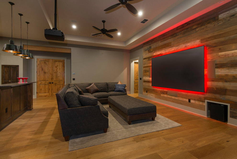 Rustic open plan home cinema in Austin with grey walls, medium hardwood flooring, brown floors and a projector screen.