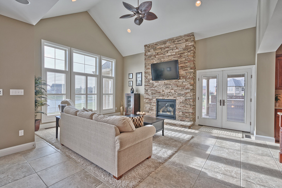 Inspiration for a large timeless open concept ceramic tile and gray floor family room remodel in St Louis with beige walls, a standard fireplace, a stone fireplace and a wall-mounted tv
