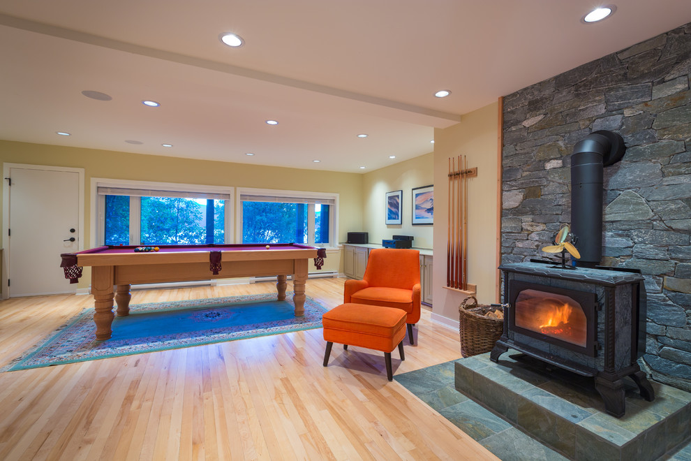 Large trendy open concept light wood floor game room photo in Vancouver with yellow walls, a standard fireplace, a stone fireplace and no tv