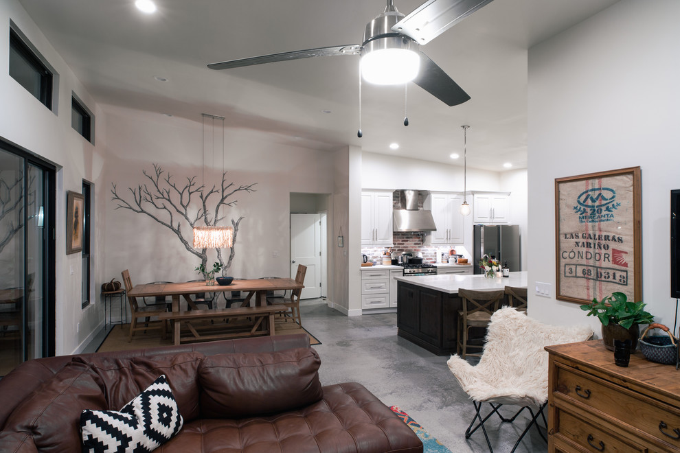 Imagen de sala de estar abierta tradicional renovada de tamaño medio sin chimenea con paredes blancas, suelo de cemento, televisor colgado en la pared y suelo gris