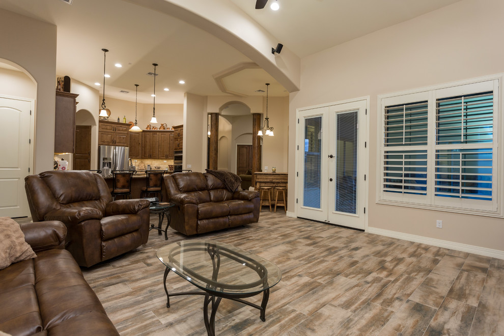 Mittelgroßes, Offenes Uriges Wohnzimmer mit beiger Wandfarbe, Kamin, verputzter Kaminumrandung, TV-Wand und braunem Holzboden in Phoenix