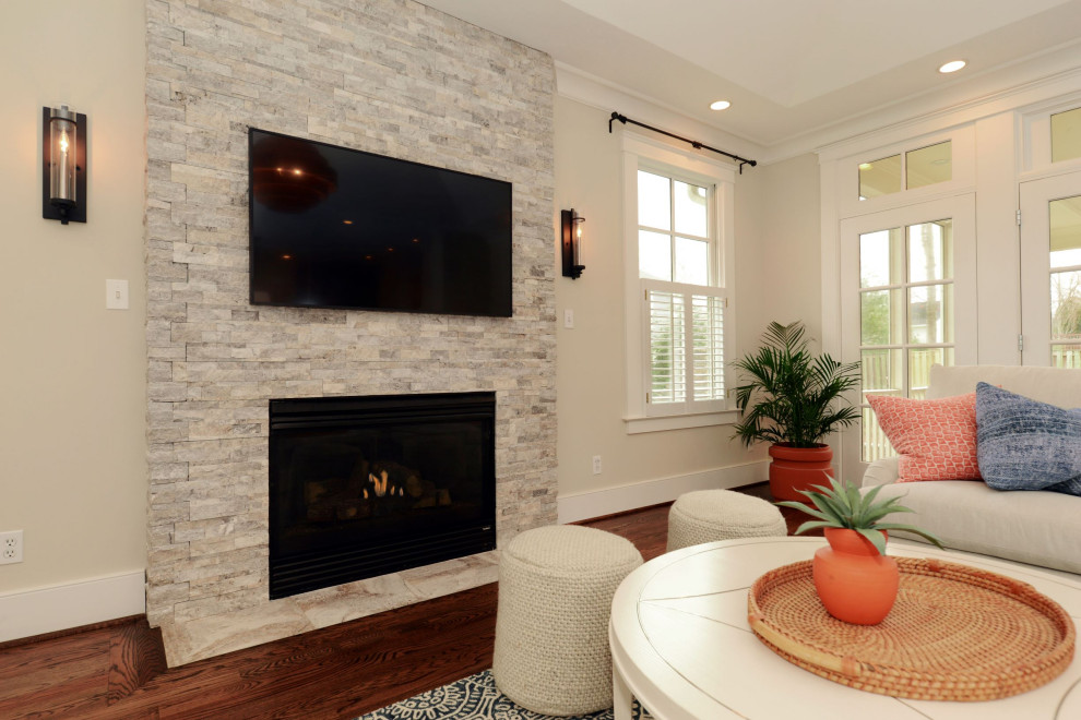 Modelo de sala de estar abierta tradicional renovada de tamaño medio con paredes beige, moqueta, todas las chimeneas, piedra de revestimiento, televisor colgado en la pared, suelo marrón y bandeja