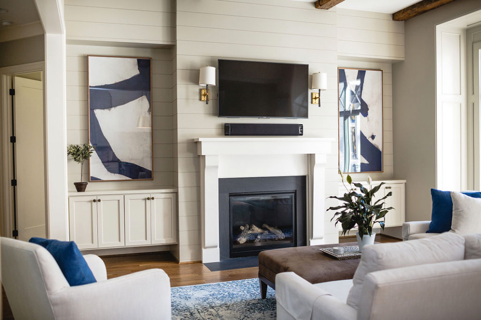 Offenes Klassisches Wohnzimmer mit beiger Wandfarbe, dunklem Holzboden, Kamin, TV-Wand, freigelegten Dachbalken und Holzdielenwänden in Raleigh