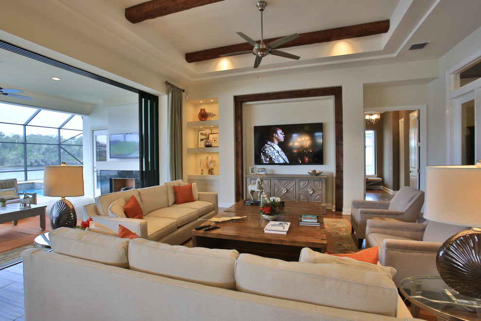 На фото: большая открытая гостиная комната в стиле фьюжн с бежевыми стенами, паркетным полом среднего тона и телевизором на стене без камина