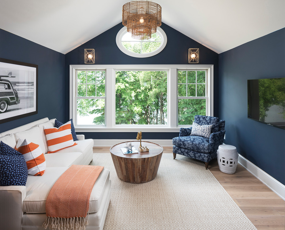 Foto de sala de estar marinera sin chimenea con paredes azules, suelo de madera clara, televisor colgado en la pared y alfombra