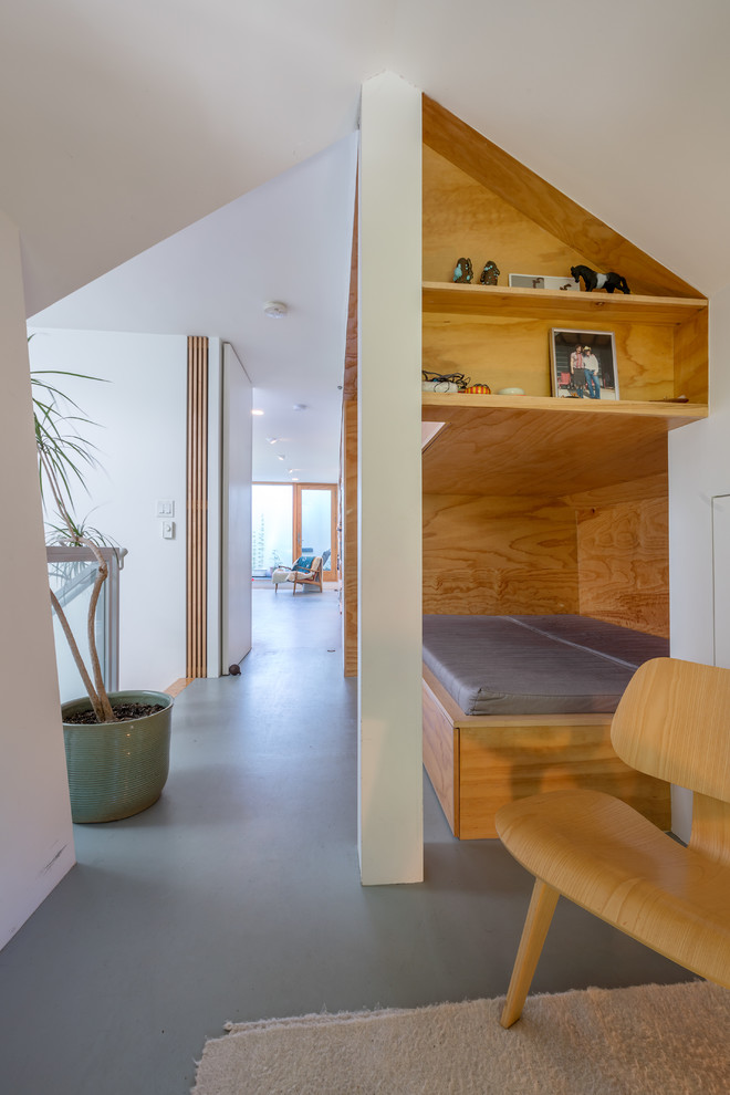 Foto di un soggiorno moderno di medie dimensioni e stile loft con libreria, pareti bianche, pavimento in compensato e pavimento grigio