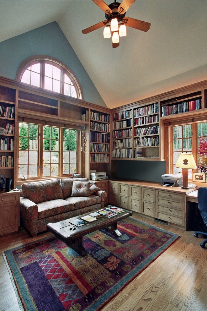 Modelo de sala de estar con biblioteca cerrada tradicional de tamaño medio con paredes verdes y suelo de madera clara