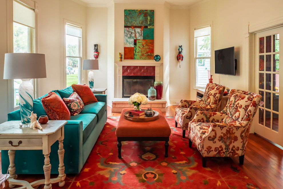 Abgetrenntes Stilmix Wohnzimmer mit Kamin, gefliester Kaminumrandung, beiger Wandfarbe, braunem Holzboden und TV-Wand in Austin