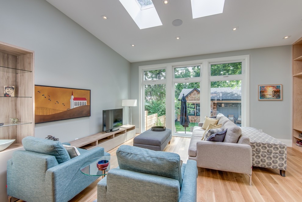 Inspiration for a large modern open plan games room in Toronto with grey walls, light hardwood flooring, no fireplace, a freestanding tv and multi-coloured floors.