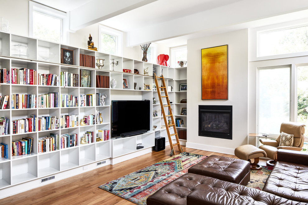 Modelo de sala de estar con biblioteca contemporánea grande con paredes blancas, suelo de madera en tonos medios, todas las chimeneas, marco de chimenea de metal, pared multimedia, vigas vistas y suelo marrón