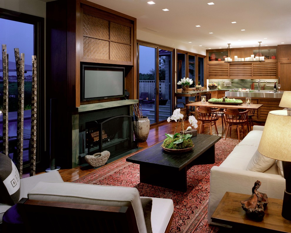 Idée de décoration pour une salle de séjour asiatique ouverte avec un sol en bois brun, une cheminée standard et un téléviseur dissimulé.