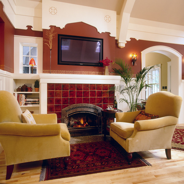 На фото: открытая гостиная комната в стиле неоклассика (современная классика) с красными стенами, паркетным полом среднего тона, стандартным камином, фасадом камина из плитки и телевизором на стене