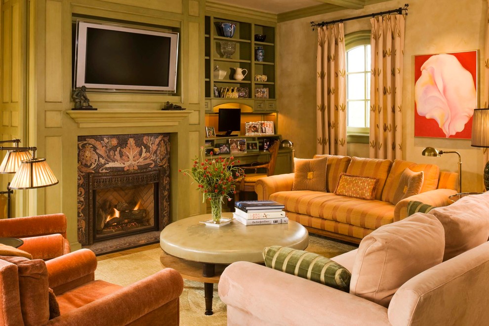 Mittelgroßes, Abgetrenntes Mediterranes Wohnzimmer mit beiger Wandfarbe, braunem Holzboden, Kamin, gefliester Kaminumrandung und TV-Wand in Denver