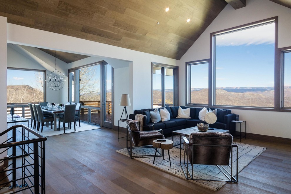 Inspiration for a mid-sized transitional open concept dark wood floor and brown floor family room remodel in Denver with white walls, a standard fireplace, a stone fireplace and a wall-mounted tv