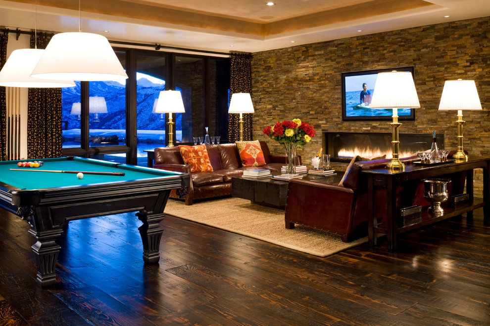 This is an example of a large contemporary open plan games room in Denver with a game room, beige walls, dark hardwood flooring, a ribbon fireplace, a stone fireplace surround, a built-in media unit and brown floors.