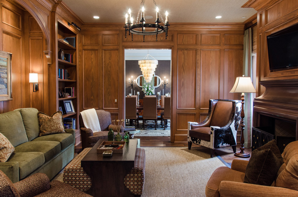 Пример оригинального дизайна: большая изолированная гостиная комната в классическом стиле с с книжными шкафами и полками, коричневыми стенами, темным паркетным полом, стандартным камином, фасадом камина из дерева и телевизором на стене