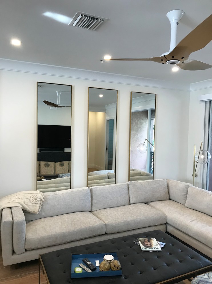 Imagen de sala de estar abierta actual de tamaño medio sin chimenea con paredes beige, suelo de baldosas de porcelana, televisor colgado en la pared y suelo marrón