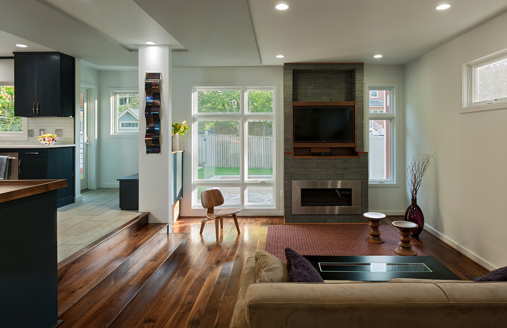 Offenes Modernes Wohnzimmer mit Gaskamin, TV-Wand, bunten Wänden, braunem Holzboden, Kaminumrandung aus Stein und braunem Boden in Washington, D.C.