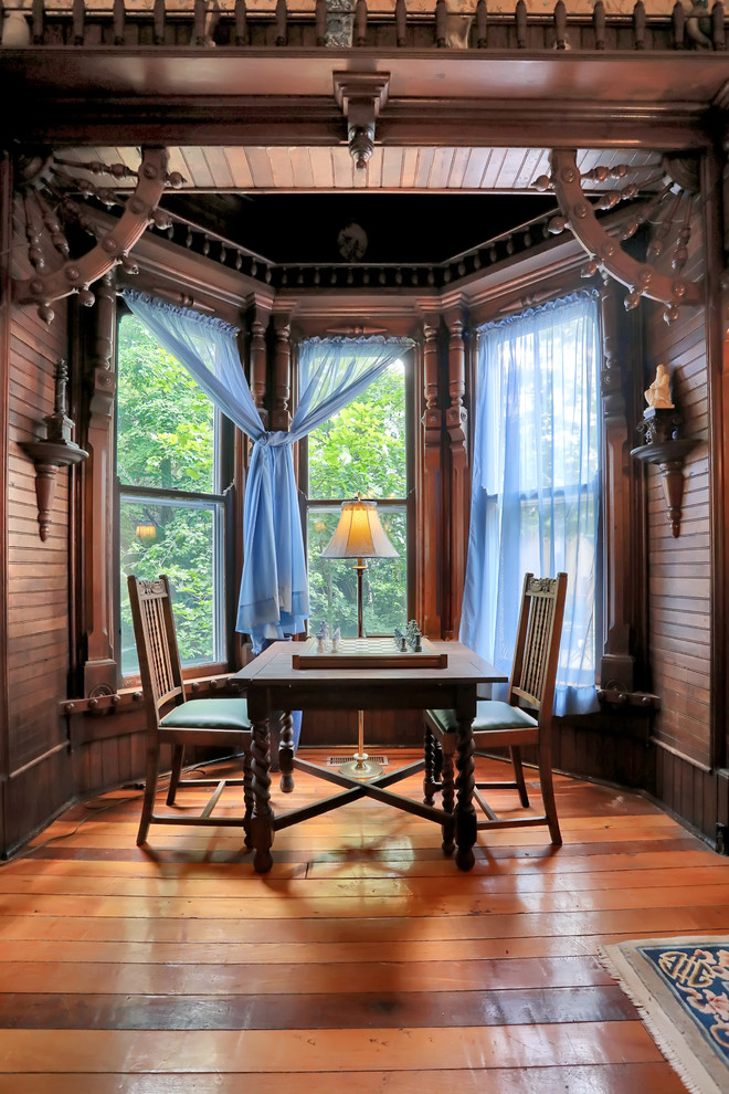 Modelo de sala de juegos en casa clásica con paredes marrones, suelo de madera en tonos medios y suelo marrón