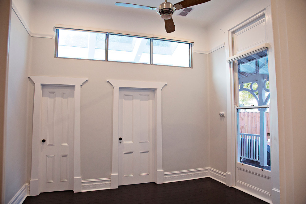 На фото: изолированная гостиная комната в классическом стиле с белыми стенами, темным паркетным полом и коричневым полом без камина