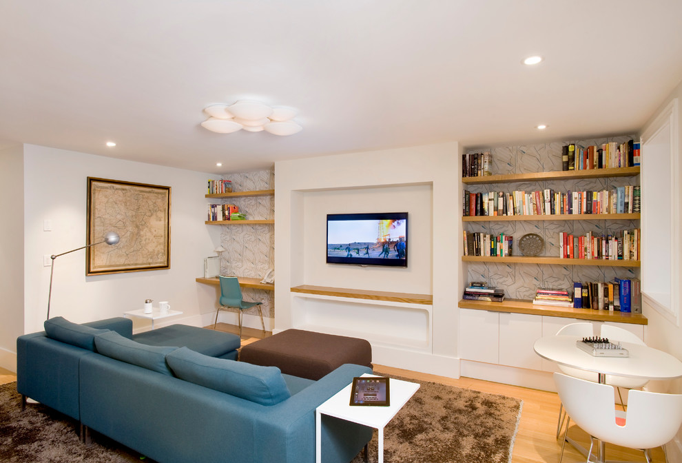 Стильный дизайн: гостиная комната в современном стиле с телевизором на стене, белыми стенами, паркетным полом среднего тона и синим диваном - последний тренд