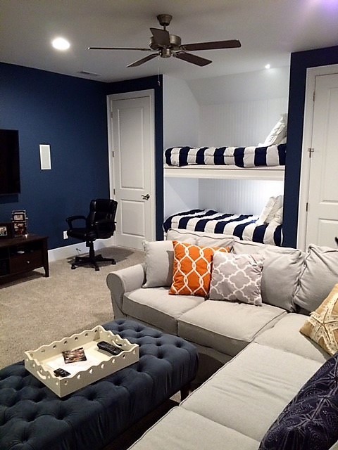 Modelo de sala de estar cerrada costera grande sin chimenea con paredes azules, moqueta, televisor colgado en la pared y suelo beige