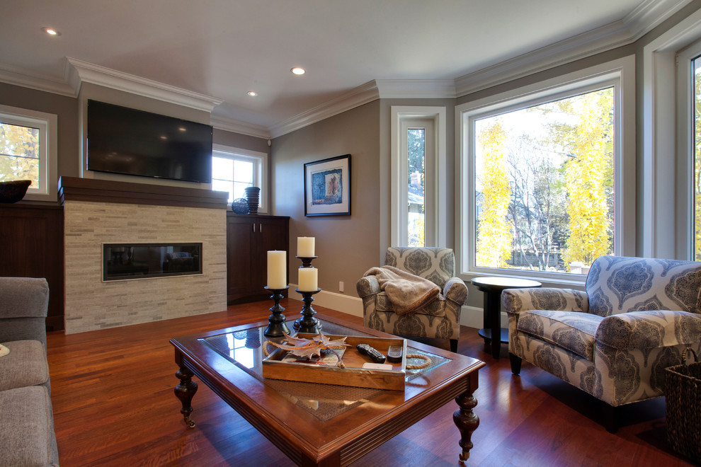 Large traditional enclosed games room in Calgary with grey walls, medium hardwood flooring, a ribbon fireplace, a stone fireplace surround and a wall mounted tv.