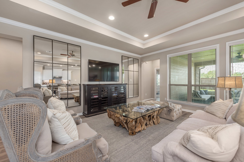 Diseño de sala de estar de estilo americano grande sin chimenea con paredes beige, suelo vinílico, televisor colgado en la pared y suelo marrón