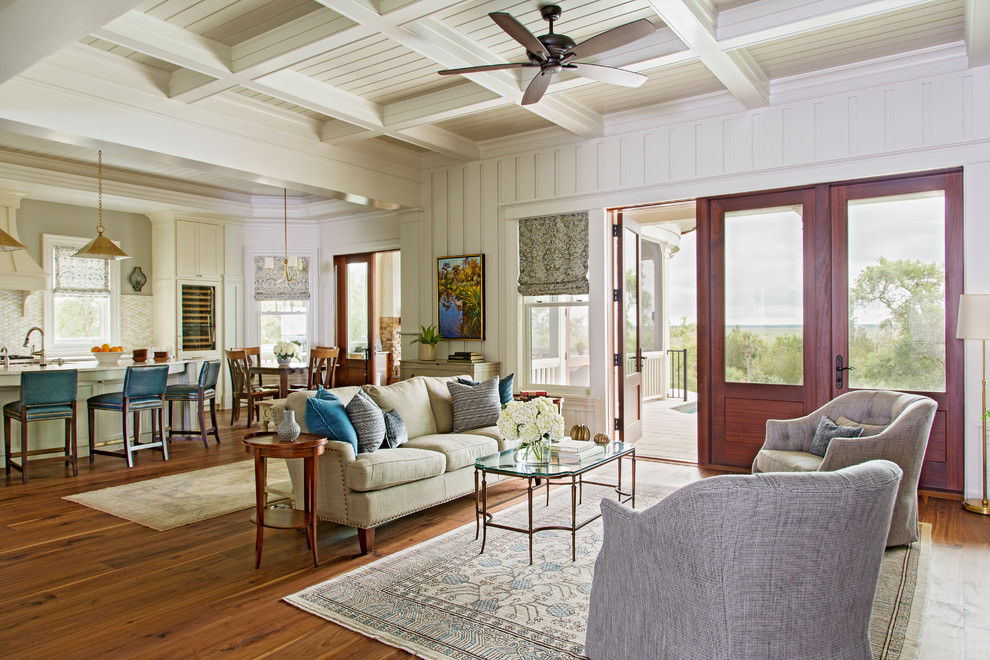 Modelo de sala de estar abierta costera grande con paredes blancas, suelo de madera en tonos medios y alfombra