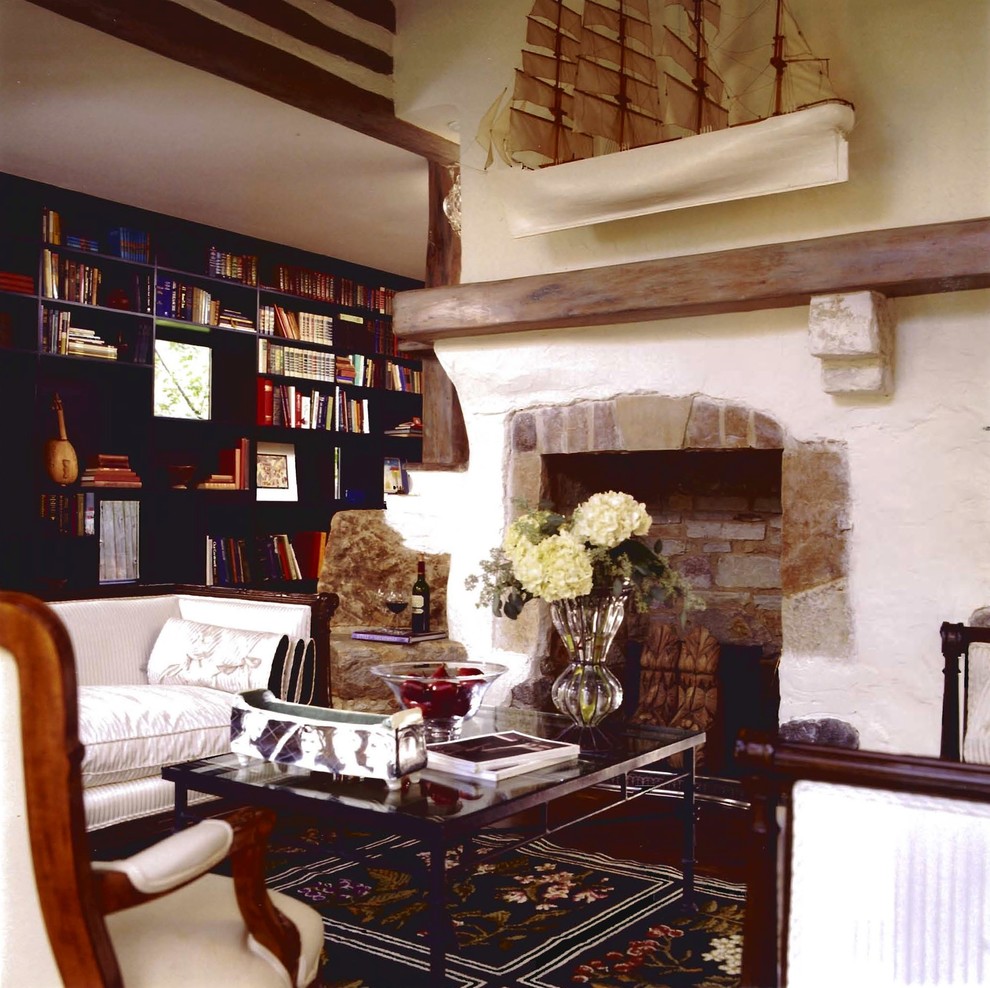 Imagen de sala de estar con biblioteca cerrada tradicional de tamaño medio sin televisor con paredes beige, todas las chimeneas y marco de chimenea de piedra