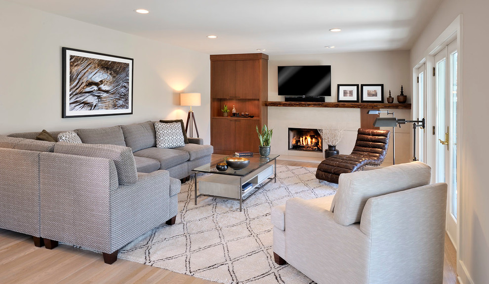 Photo of a contemporary games room in New York with beige walls, light hardwood flooring, a standard fireplace, a wall mounted tv and a concrete fireplace surround.